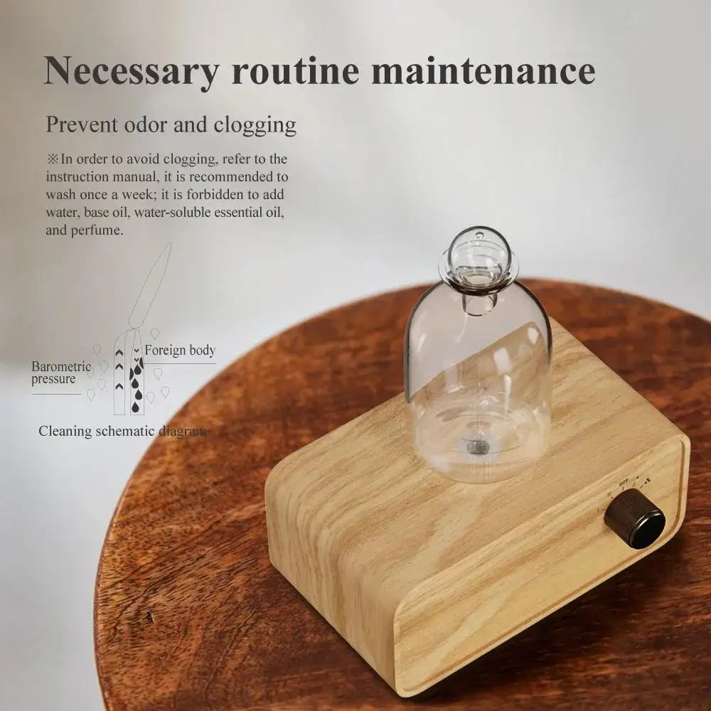 Essential oil diffuser with clear glass bottle and light wood base on brown tabletop