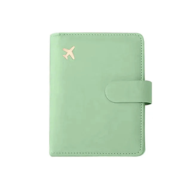 Sage green passport folio with stitched edges and snap strap, embossed airplane icon