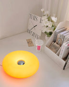 Yellow donut table lamp on a white shelf, centered circular top opening