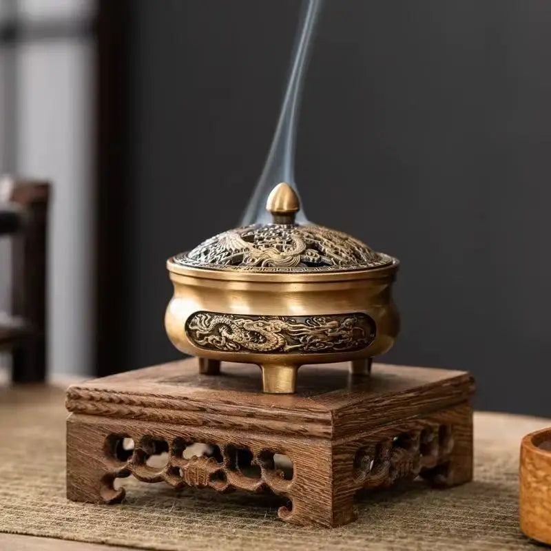 Brass engraved incense plate burner on stand, flame stream rising from the top opening