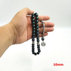 Tasbih misbaha held in hand, faceted green-blue beads with silver-tone beads and charm