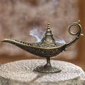 Antique lamp candle burner with ornate brass-tone body and flame cup on base