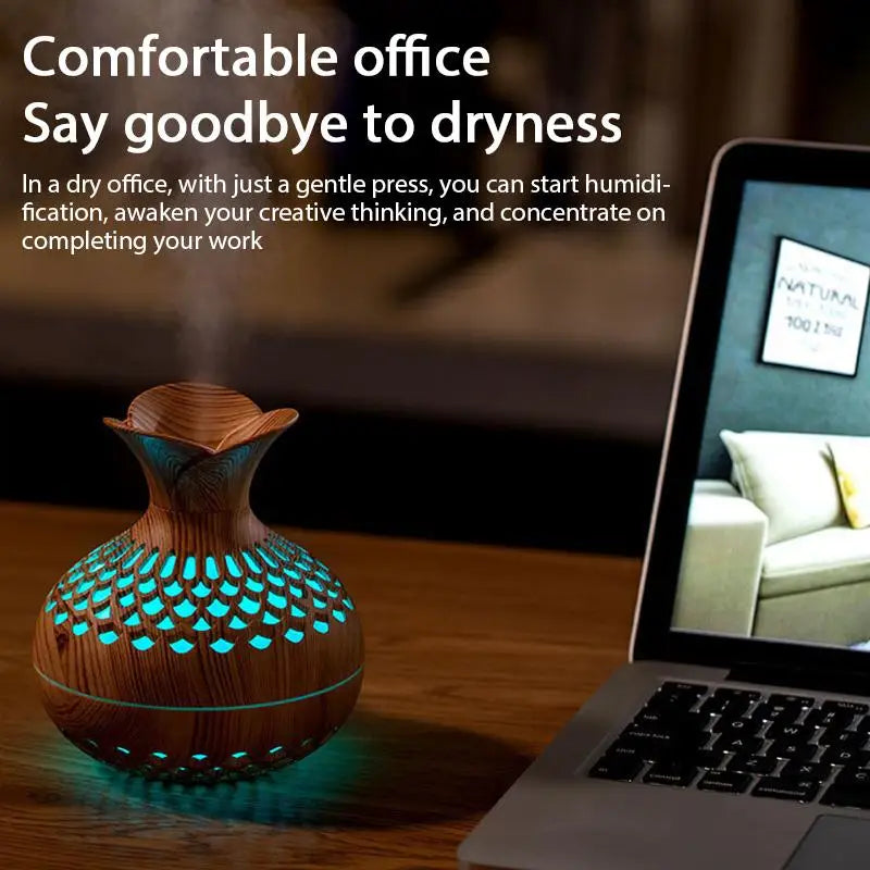 Wood grain mini vase humidifier with teal LED glow beside a laptop
