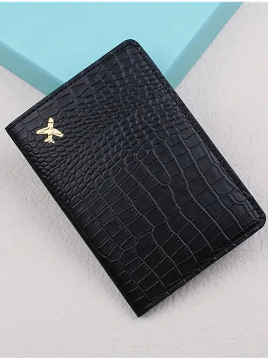 Black croc-embossed passport holder angled view with gold airplane emblem