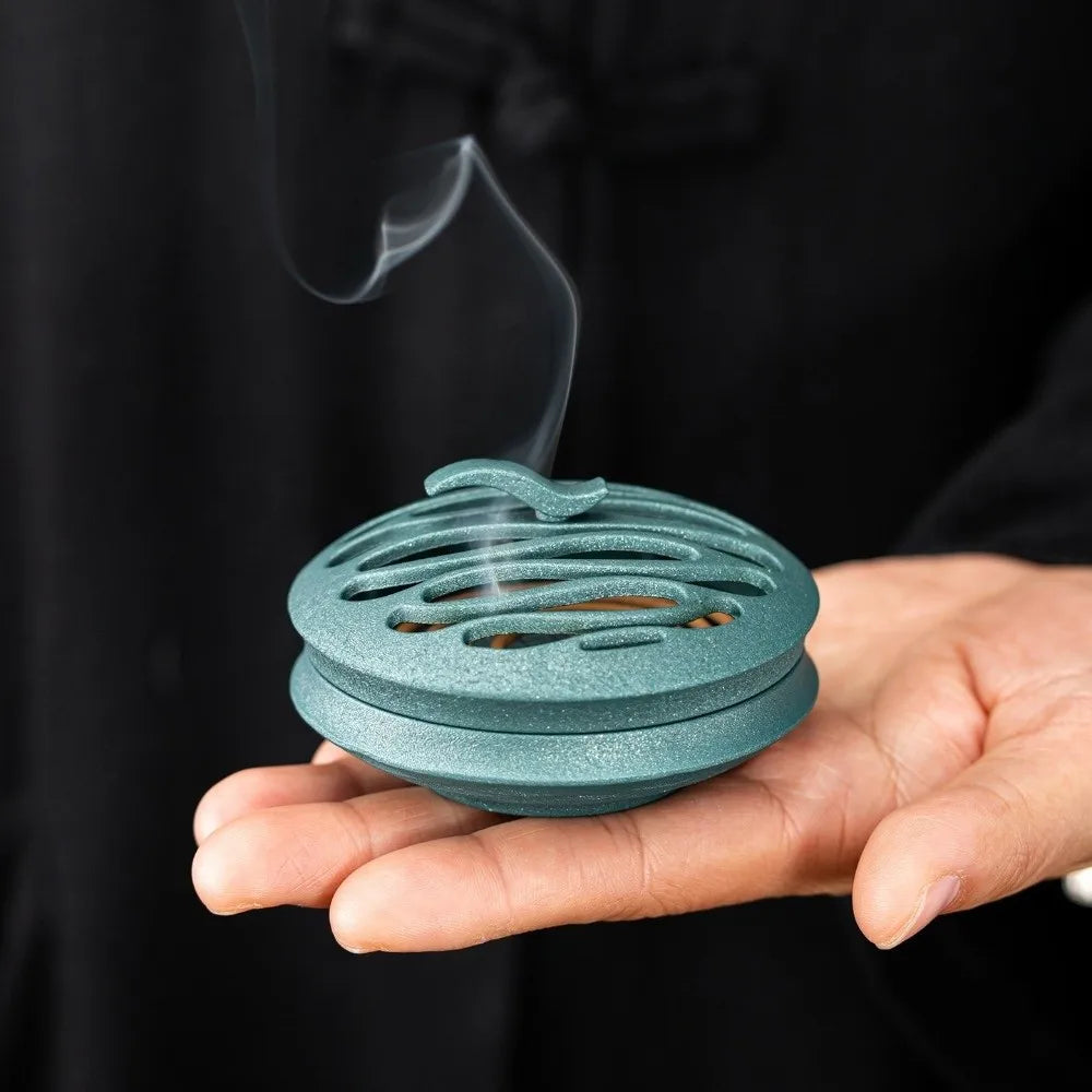 Teal/blue round hollow incense burner with flame rising from the center holes