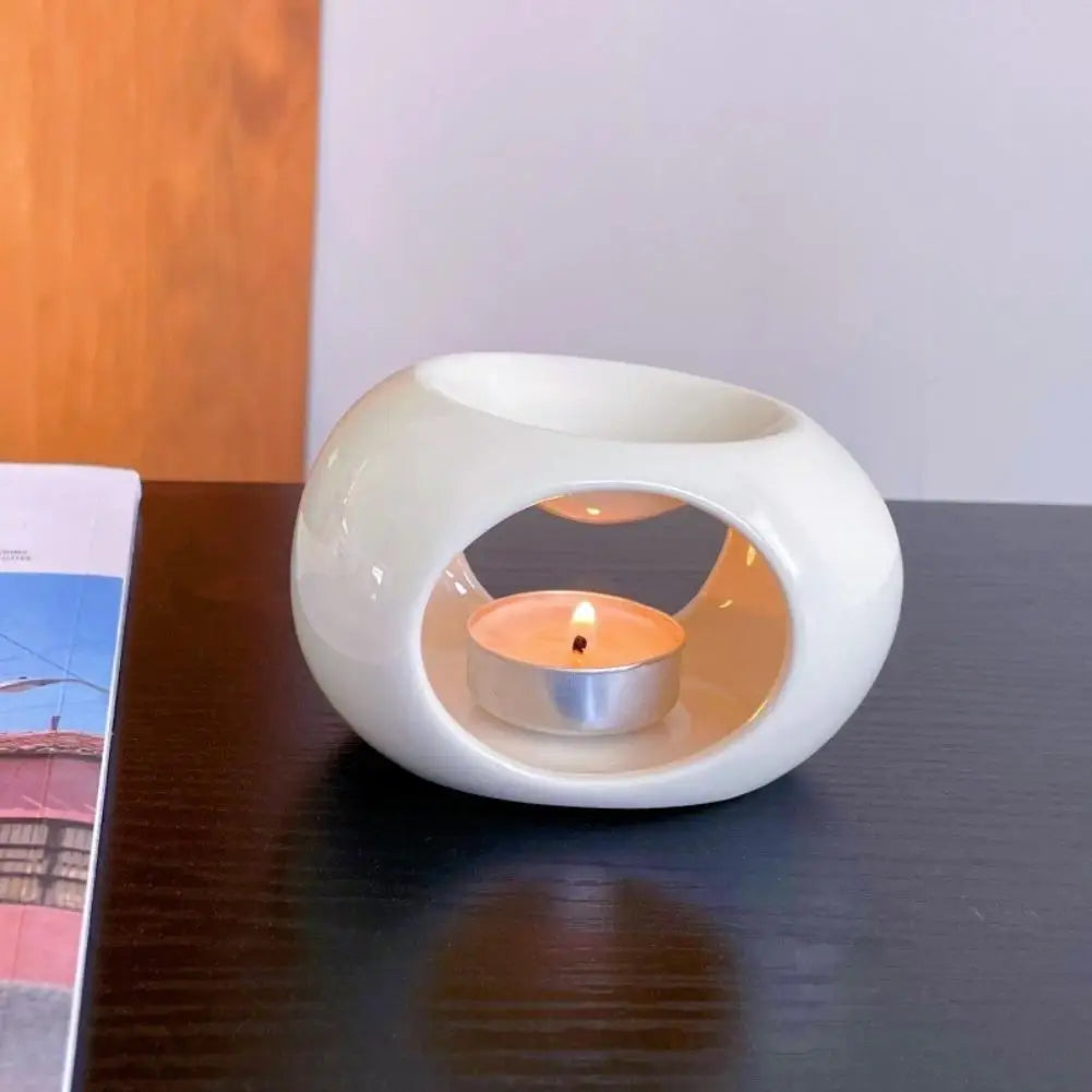White ceramic aroma oil burner with circular window and lit tea candle