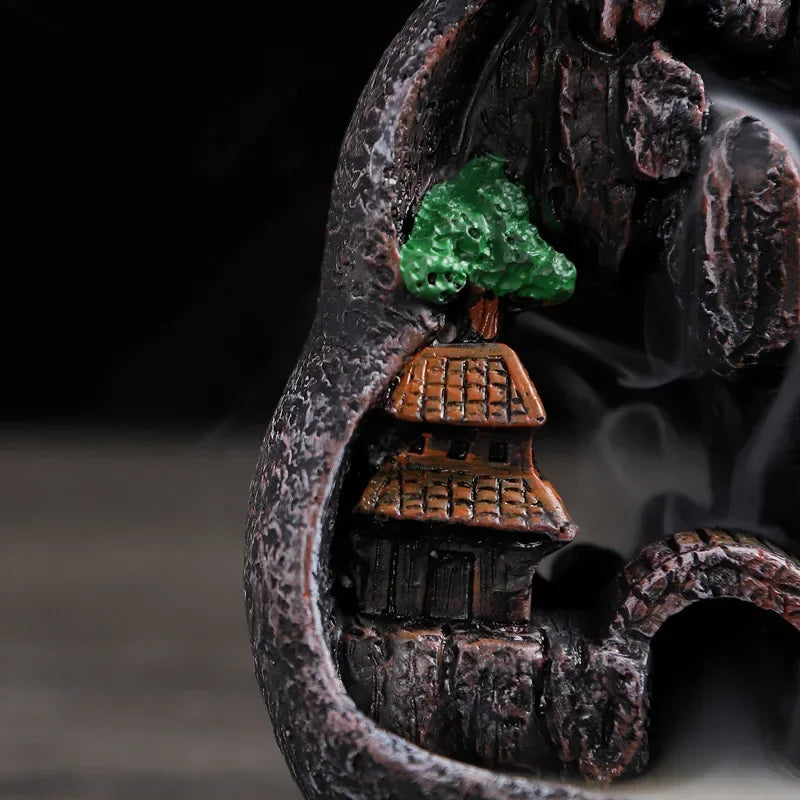Resin waterfall incense burner detail: arched rocks, orange-roof building, green tree beside smoke