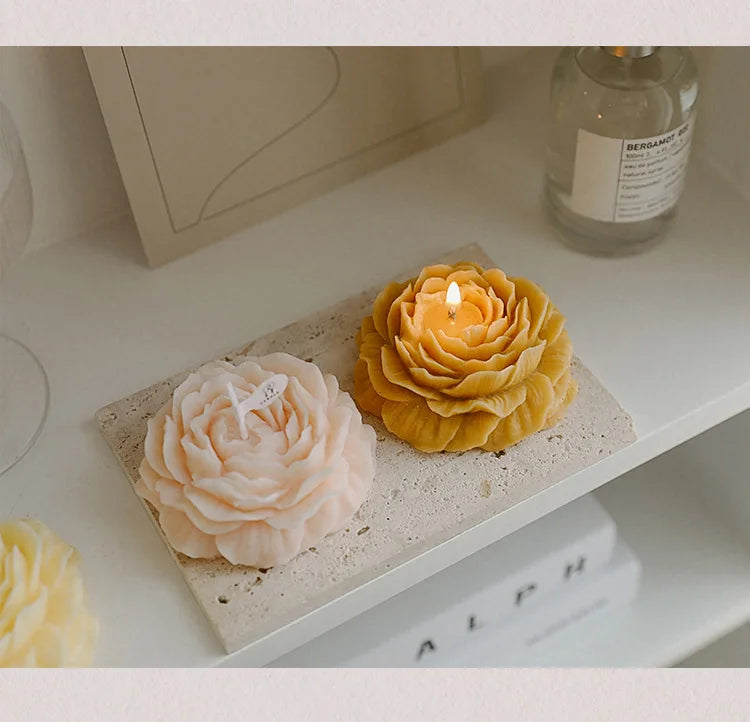Yellow and cream peony sculptural candles with lit wicks on a tray