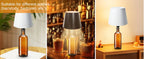 Wine bottle wireless LED lamp with white fabric shade on tabletop, amber bottle base