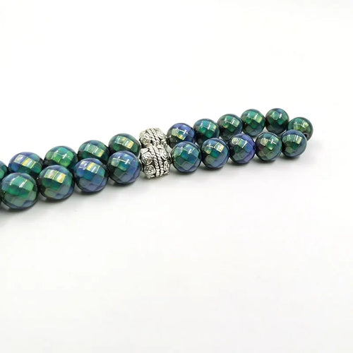 Tasbih rosary with green-blue faceted beads and silver-toned clasp, single strand close-up.