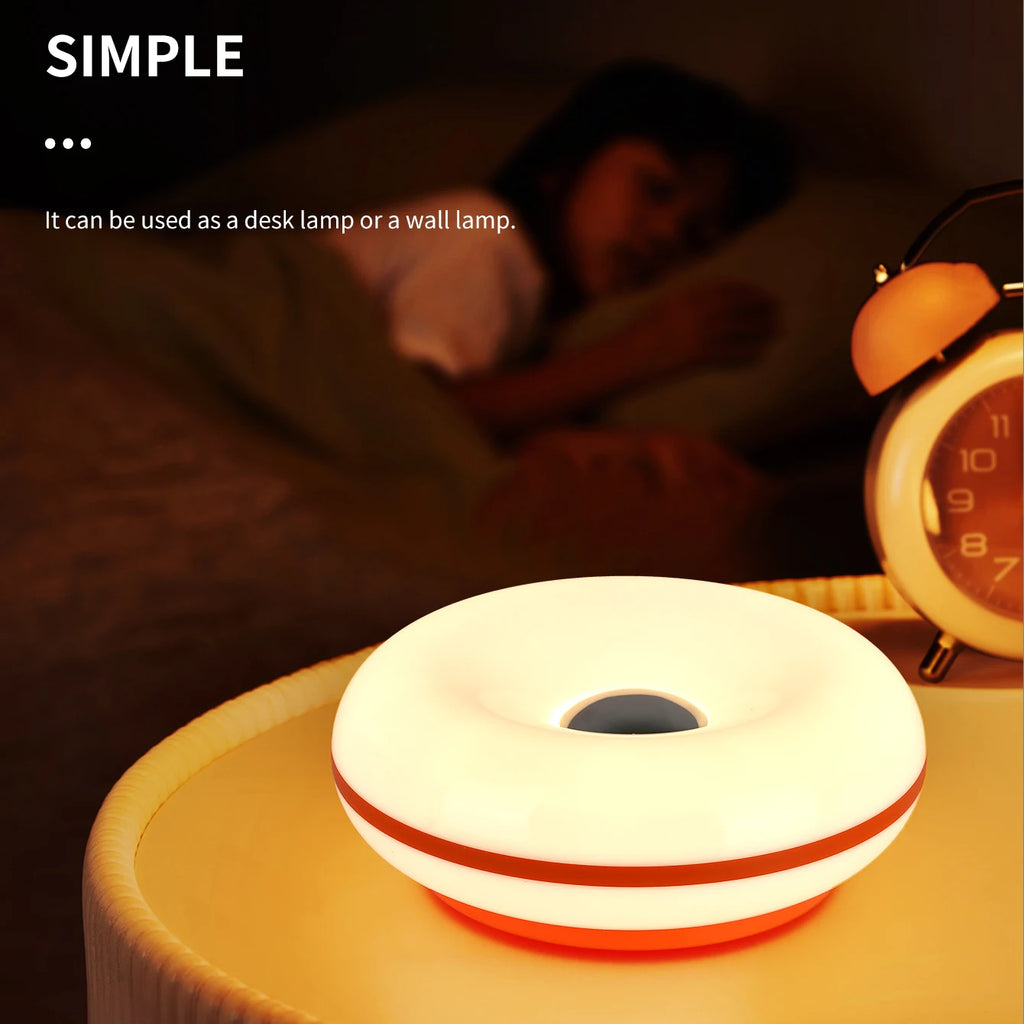 Glowing white donut table lamp on tabletop, warm light from center opening.