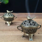 Copper lotus incense burner with bird-topped lid on tripod-like feet, embossed body