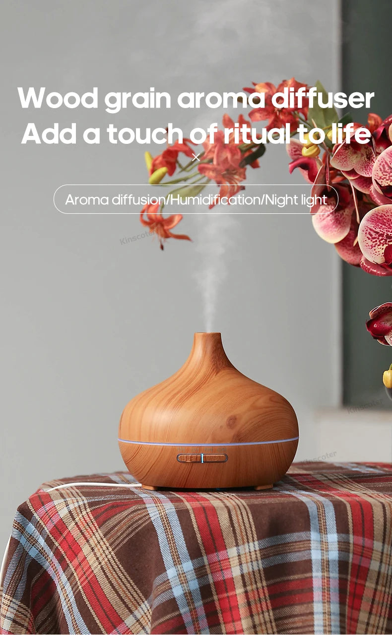 Light wood aroma diffuser with glowing button and mist beside flowers