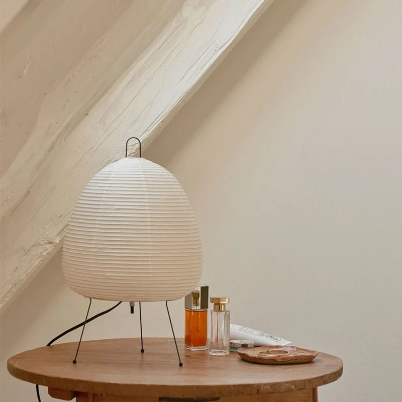 Unlit white paper lantern lamp on tripod legs with arched handle and black base frame