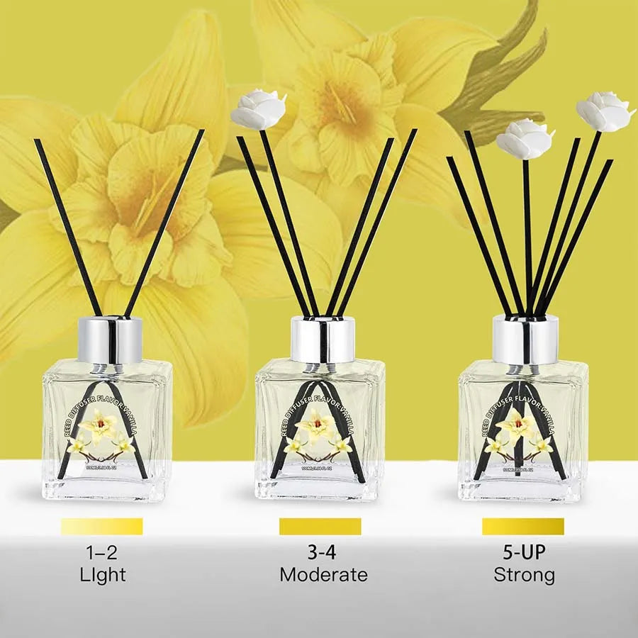 Three glass reed diffusers with black reeds and white flower garnish