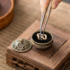 Brass pocket incense burner with open base and black insert holding incense sticks