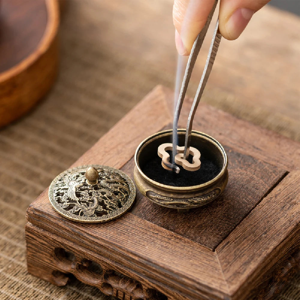Brass pocket incense burner with open base and black insert holding incense sticks