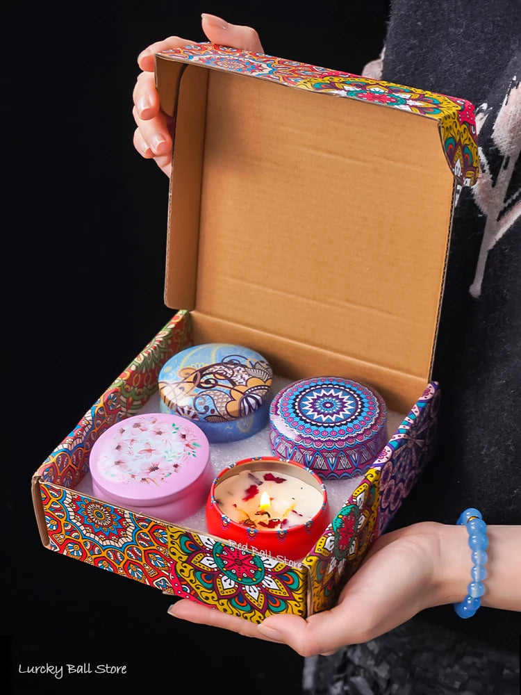4-piece scented candle gift set in open box with three patterned tins and one lit