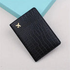 Black croc-embossed passport sleeve with gold airplane emblem, front view