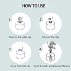Reed diffuser bottle with black reeds and white rose flower in the glass