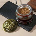 Ceramic electric incense warmer with metal insert filled with fine brown incense