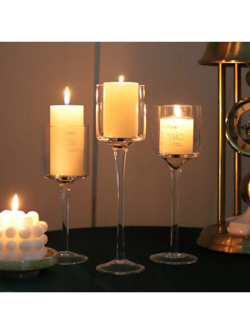Tall glass candle holder trio with three lit pillar candles in clear cups