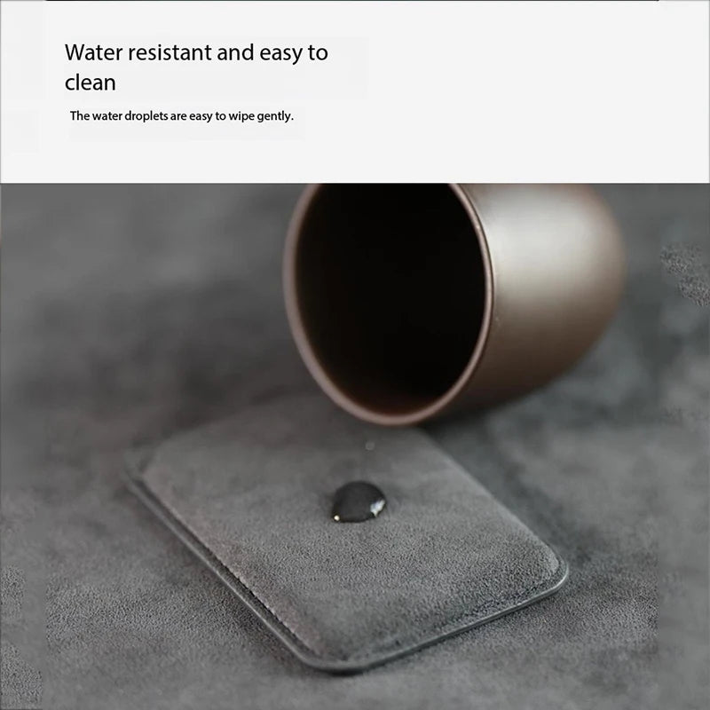Dark gray Alcantara MagSafe wallet with a water droplet on textured surface