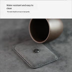 Dark gray Alcantara MagSafe wallet with a water droplet on textured surface