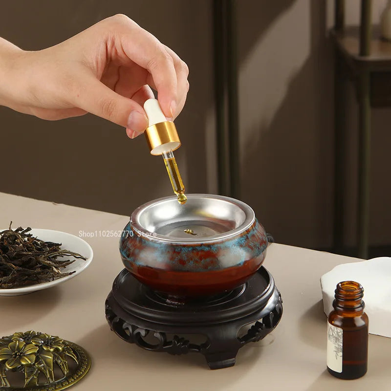 Ceramic electric incense warmer with metal dish as oil is poured into the burner top