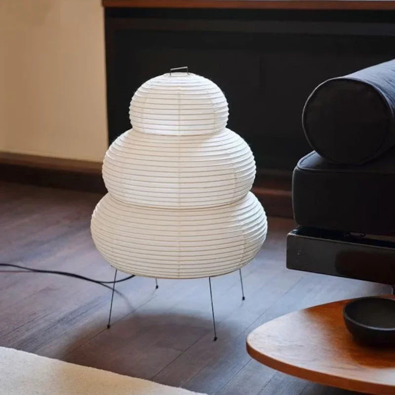 White paper artisan bedside lamp with layered dome shade and black tripod legs