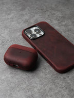 Burgundy leather AirPods case with rounded cover and side charging cutout