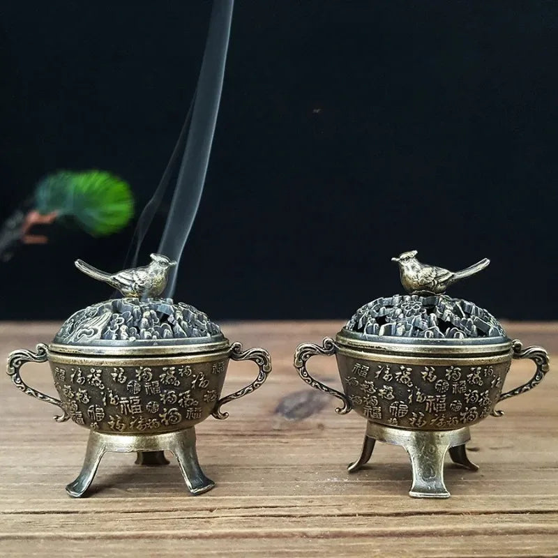 Pair of copper lotus incense burners with bird-topped lids and lifted incense sticks
