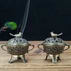 Pair of copper lotus incense burners with bird-topped lids and lifted incense sticks