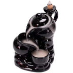 Black glossy backflow incense burner with two-tier hand design and conical incense