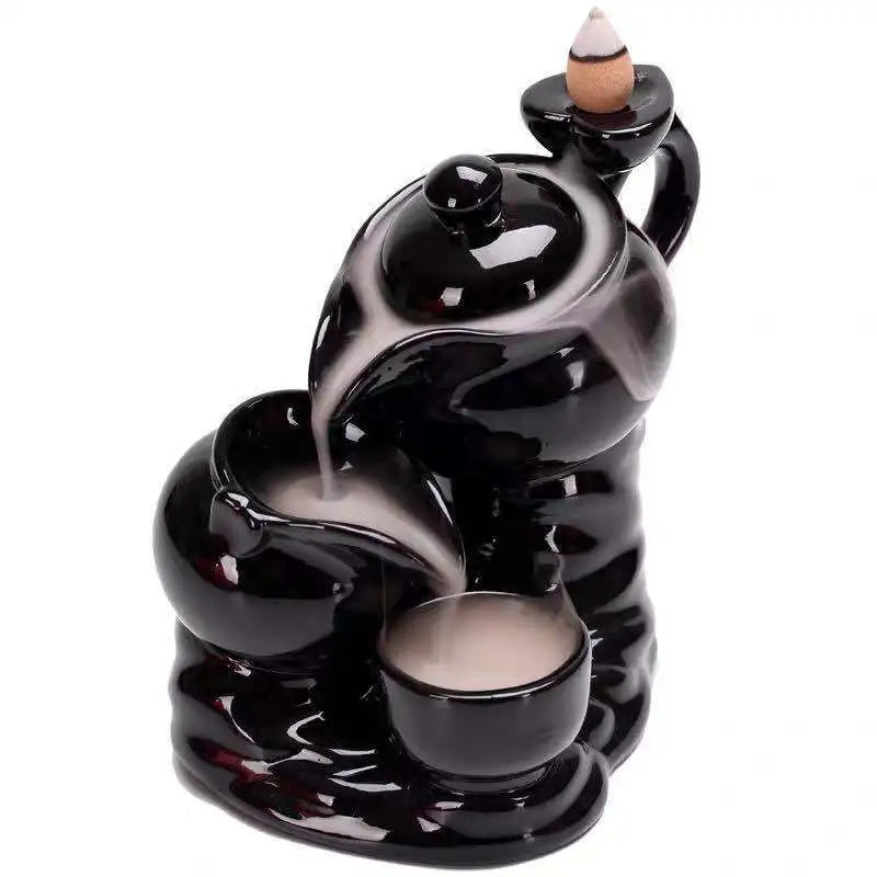Black glossy backflow incense burner with two-tier hand design and conical incense