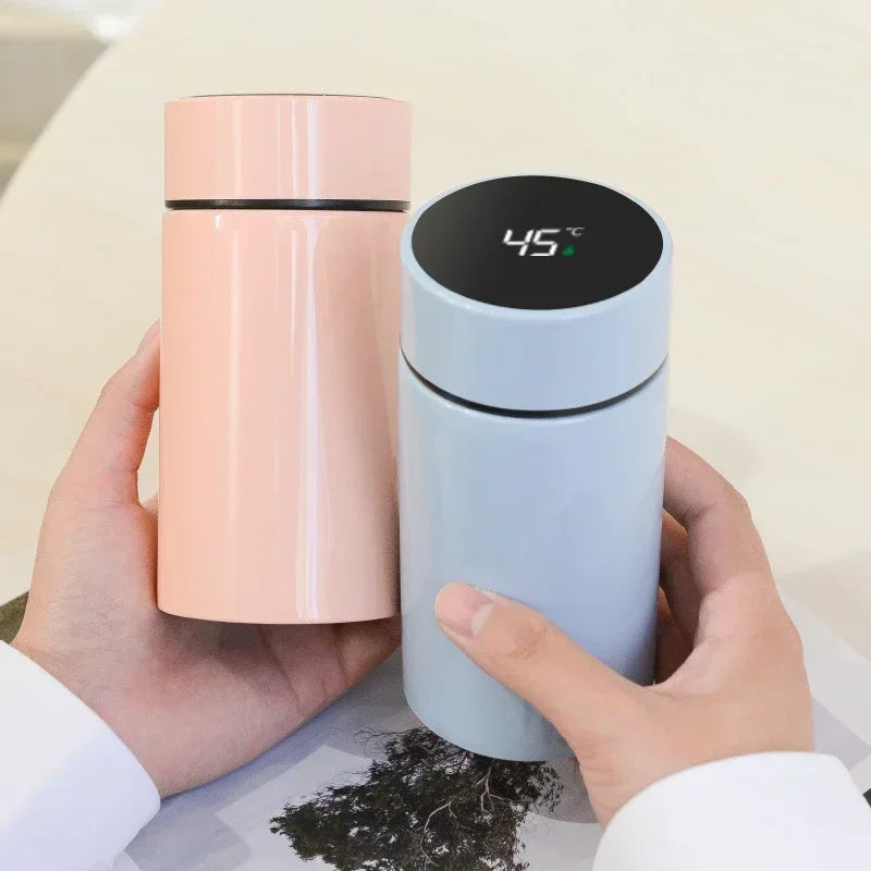 Hands holding pink and light blue compact thermos bottles, digital displays