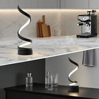 Spiral LED lamp in black, glowing zigzag light shape on countertop with black base