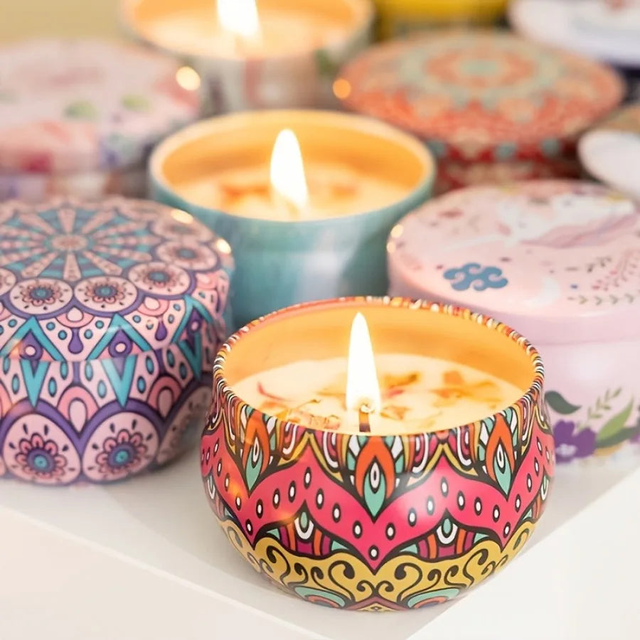 Colorful patterned scented candle jar with lit flame, with other tins nearby