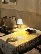 White desk lamp emitting a warm light on a tabletop