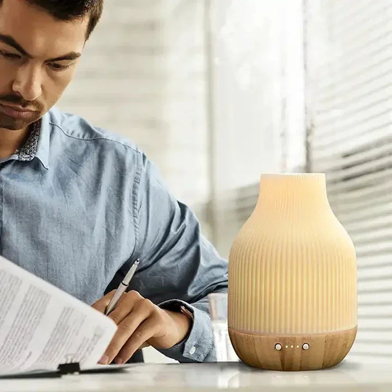 Ceramic aroma diffuser on desk, white top and wood base with front control buttons