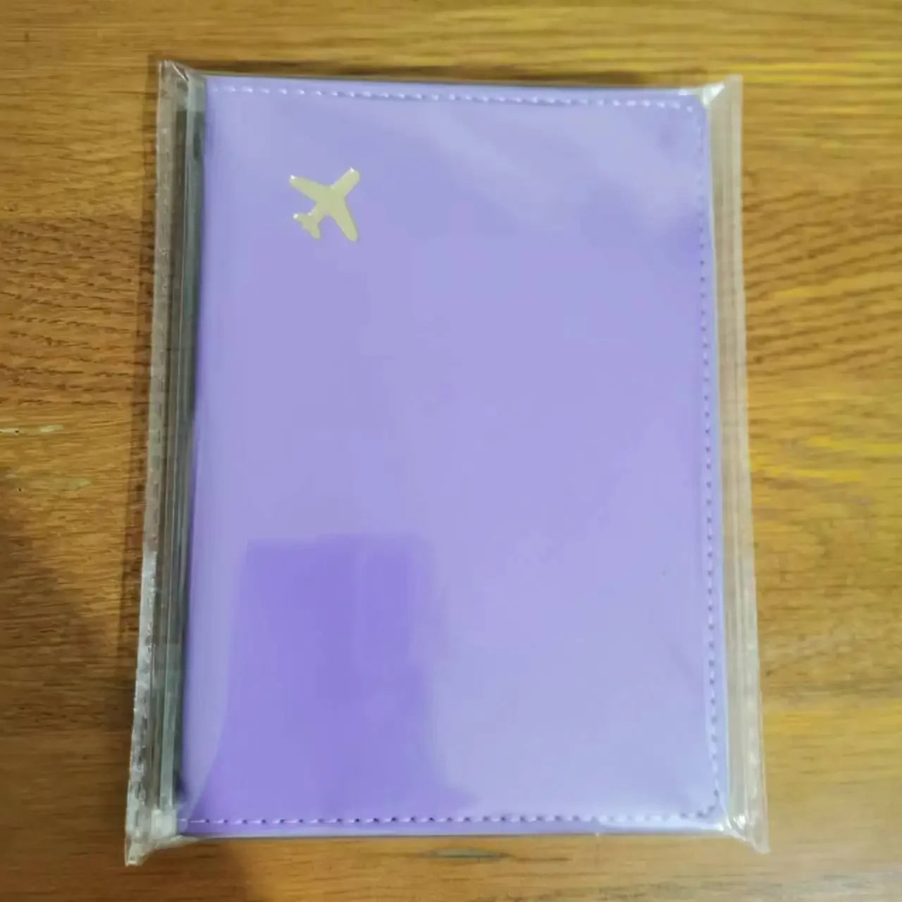 Dusty violet passport sleeve with gold airplane emblem and stitched border