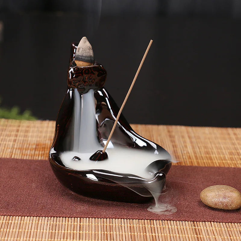 Backflow incense tower burner in glossy black with cone incense and rising smoke