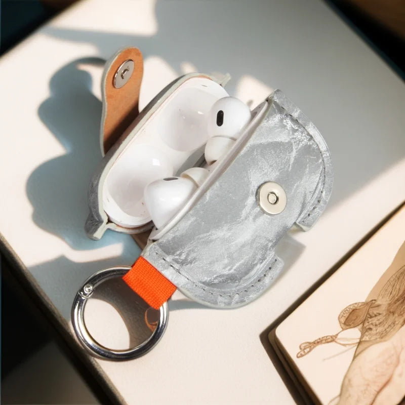 Silver PU AirPods cover with orange strap, silver key ring, and snap button