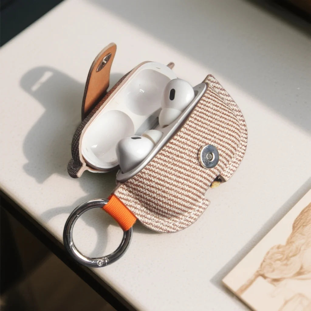 Soft PU AirPods cover in tan herringbone fabric with orange strap and silver key ring