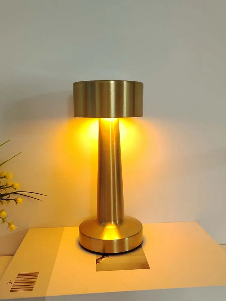 Retro table lamp with brushed gold cylindrical body and dome shade, warm light on