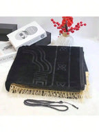 Velvet padded prayer rug in black with raised arch pattern and cream fringe trim, plus beads.