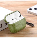 Olive green crocodile-grain AirPods case opened, showing earbuds inside