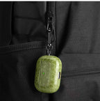 Olive green crocodile-grain AirPods case hanging from zipper pull with clip