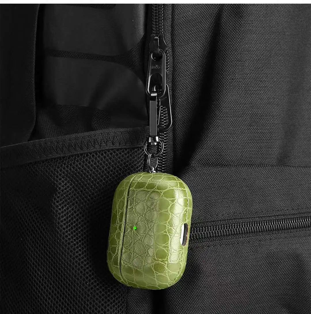 Olive green crocodile-grain AirPods case hanging from zipper pull with clip