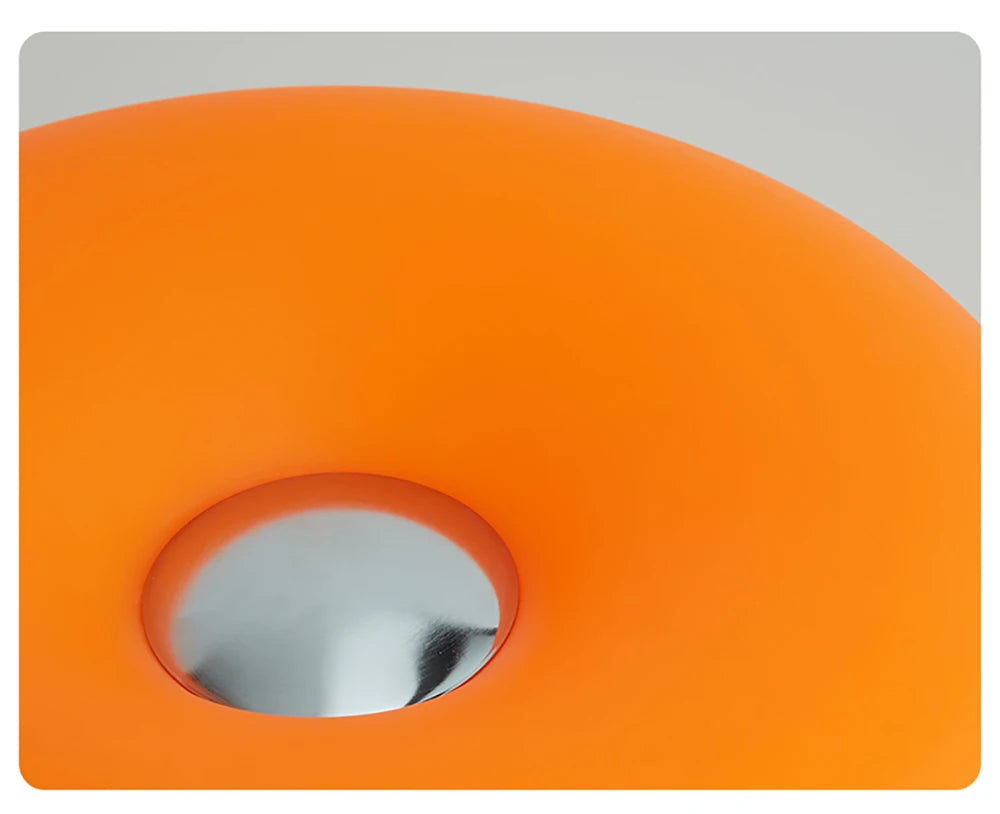 Orange donut table lamp with center circular opening and glossy metallic insert